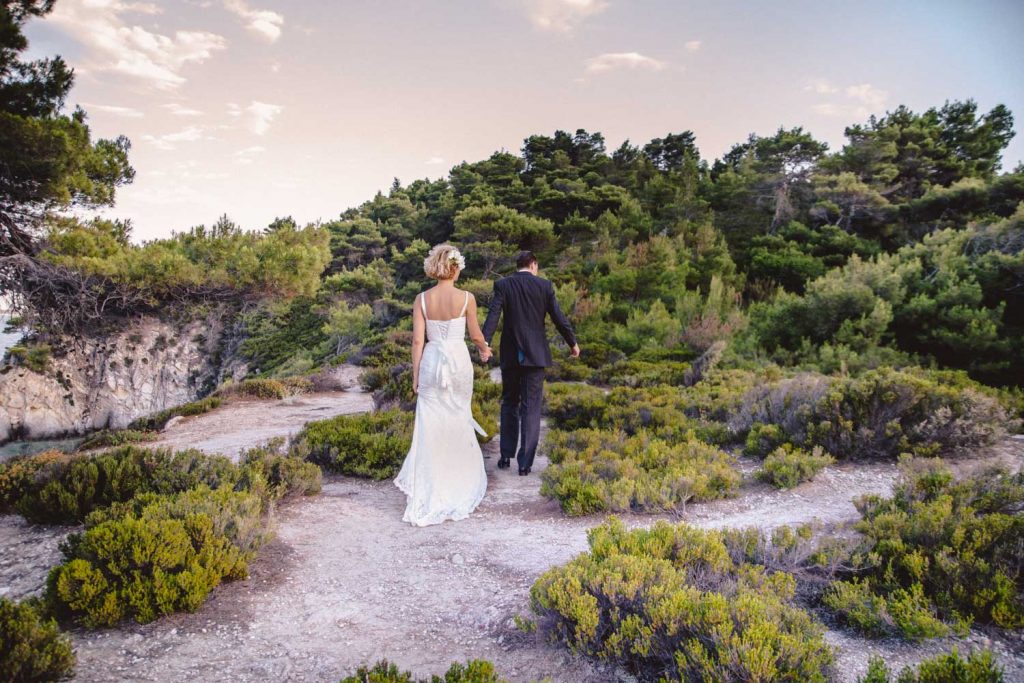 Das Brautpaar spaziert in Anzug und Hochzeitskleid durch die Natur