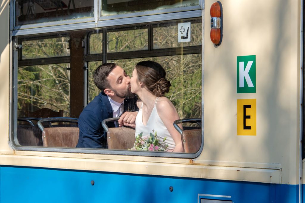 Die Hochzeitsfotografin beobachtet, wie sich das Brautpaar in der alten Tram küsst