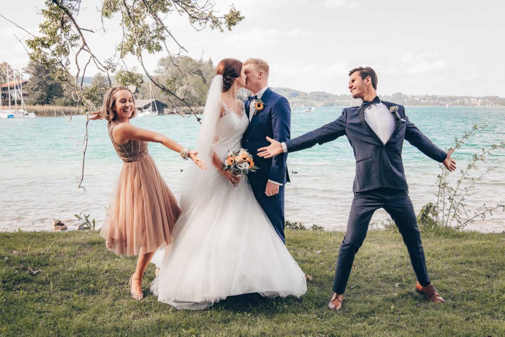 Ein etwas andere Hochzeitsfoto mit Brautpaar und den Trauzeugen am Ufer des Tegernsee in Bad Wiessee