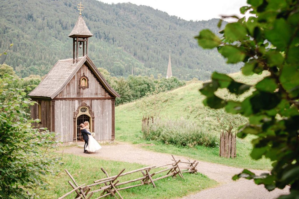 Fest umarmt sich das Brautpaar vor der Kapelle im Wasmeier Freilichtmuseum