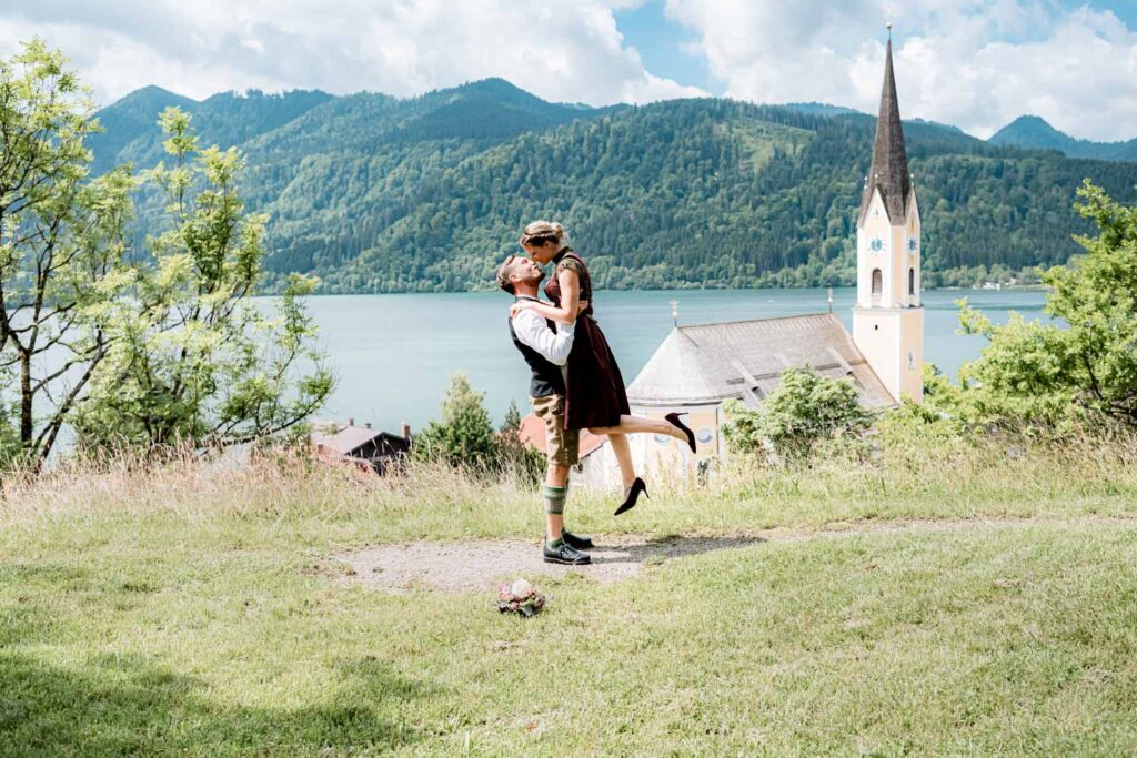 Der starke Bräutigam hebt seine Braut für einen Kuss vor der traumhaften Kulisse am Schliersee - ein echt starkes Brautpaarportrait