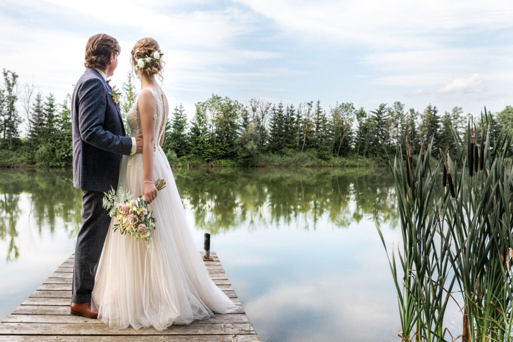 Das Brautpaar genießt seine freie Trauung und Gartenhochzeit bei Ingolstadt und posiert auf dem Steg am kleinen See im Norden von München