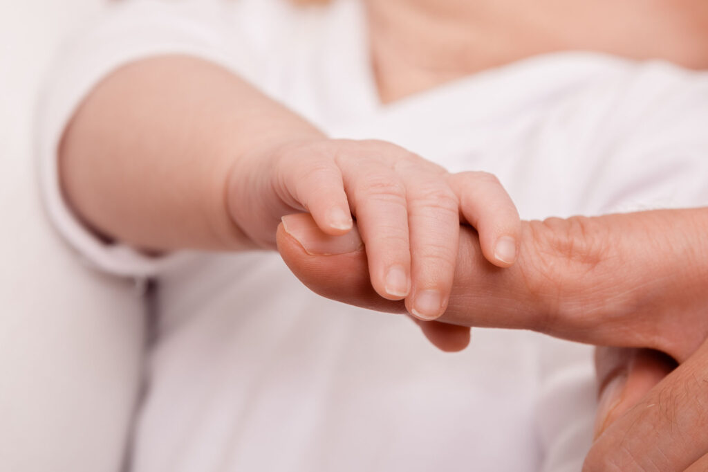 Kleine Hand des Babys hält sich am Zeigefinger fest. Ein Neugeborenen Baby Fotoshooting ist mit einem Hausbesuch von Johanna Schmidt Fotografie ganz einfach und unkompliziert in München und seiner Umgebung möglich.