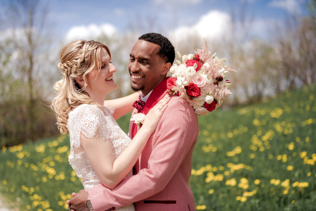 Das Brautpaar umarmt sich in der Blumenwiese beim Fotoshooting